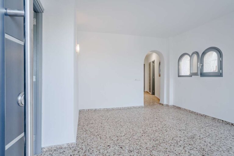 Living area with white walls, tiled flooring and arched doorway inside an independent apartment at a Mediterranean villa in Maryvilla, Calpe.