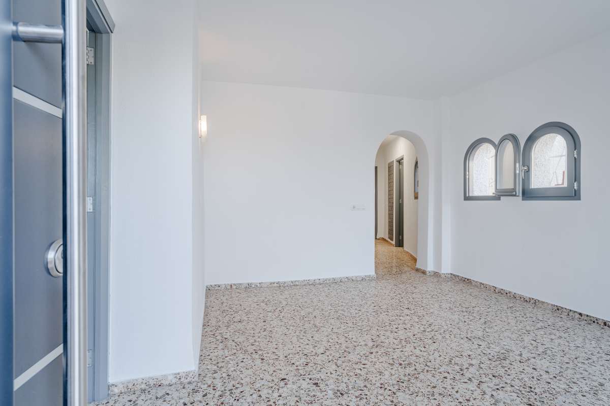 Living area with white walls, tiled flooring and arched doorway inside an independent apartment at a Mediterranean villa in Maryvilla, Calpe.