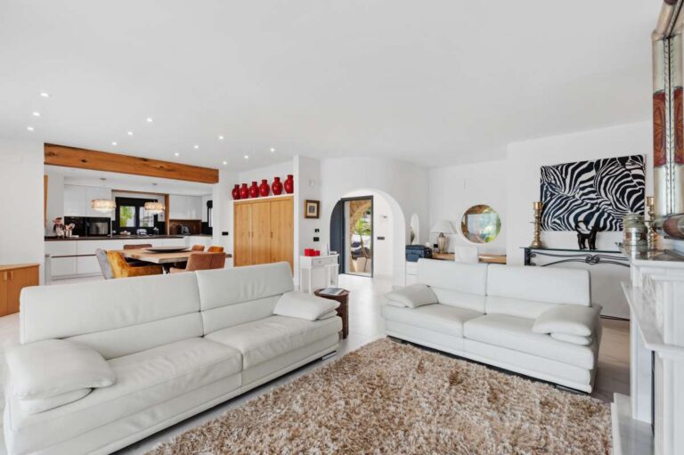 Living room and kitchen area inside a premium coastal villa on the Benissa Costa with white sofa seating, open-plan layout and modern interior finish