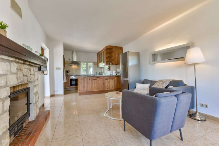 Living room and kitchen inside a charming Benissa Coast villa with stone fireplace, open-plan layout, air conditioning and bright interior finish