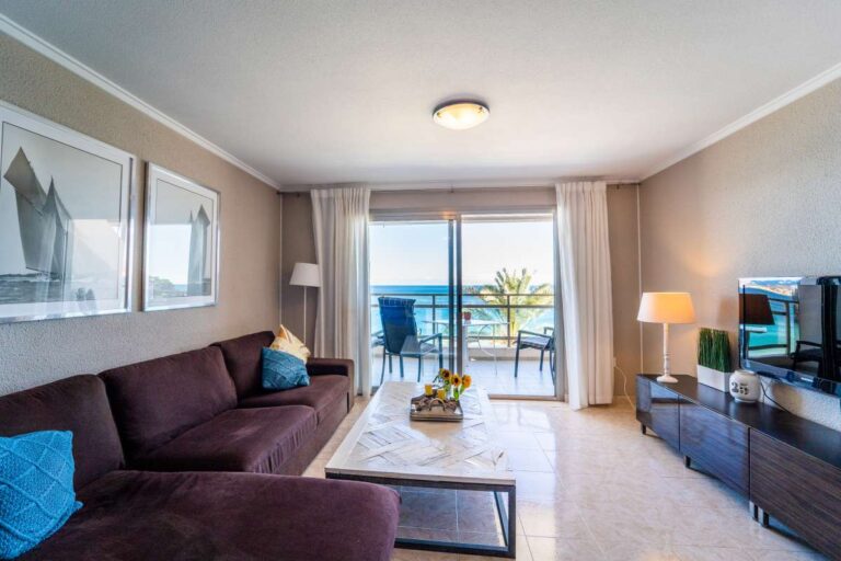 Living room inside a beachfront apartment by La Fossa Beach in Calpe with sofa seating, terrace access and sea views beyond