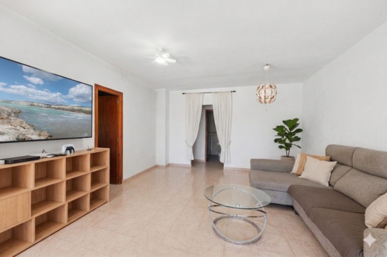 Living room inside a Mediterranean villa in Benissa Costa with TV area, sofa seating, tiled floor and bright white interior