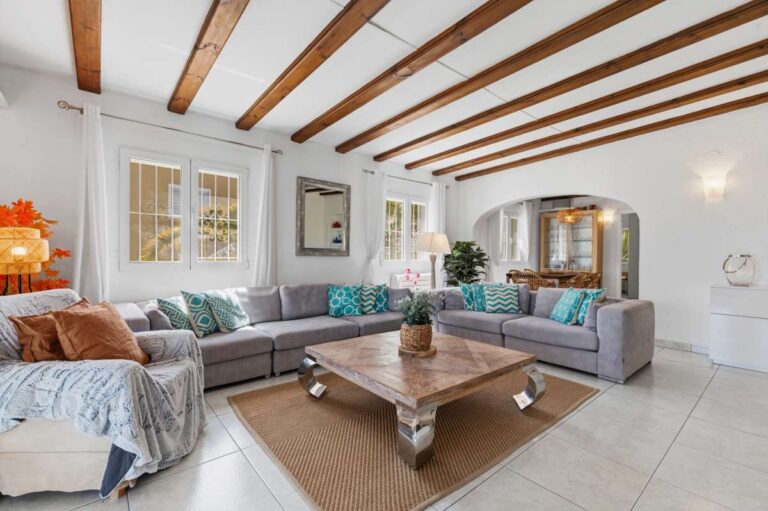 Living room inside a renovated Moraira villa with exposed beams, sofa seating, wooden coffee table and bright open-plan layout