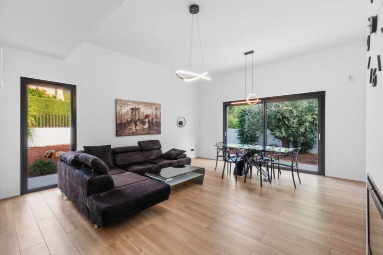 Living room inside a single-level modern villa in Santa Clara, Altea with sofa seating, dining area, large sliding doors and garden access