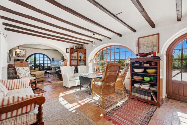 Living room inside a traditional Spanish finca near Moraira with arched windows, beamed ceiling, rustic furniture and Mediterranean character