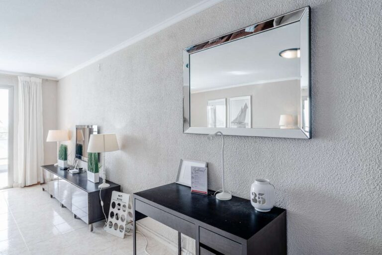 Living room TV area inside a beachfront apartment by La Fossa Beach in Calpe with mirror, media unit and bright interior finish
