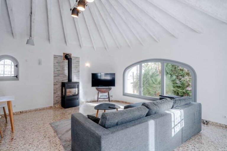 Living room with fireplace, sofa and beamed ceiling inside a Mediterranean villa in Maryvilla, Calpe.