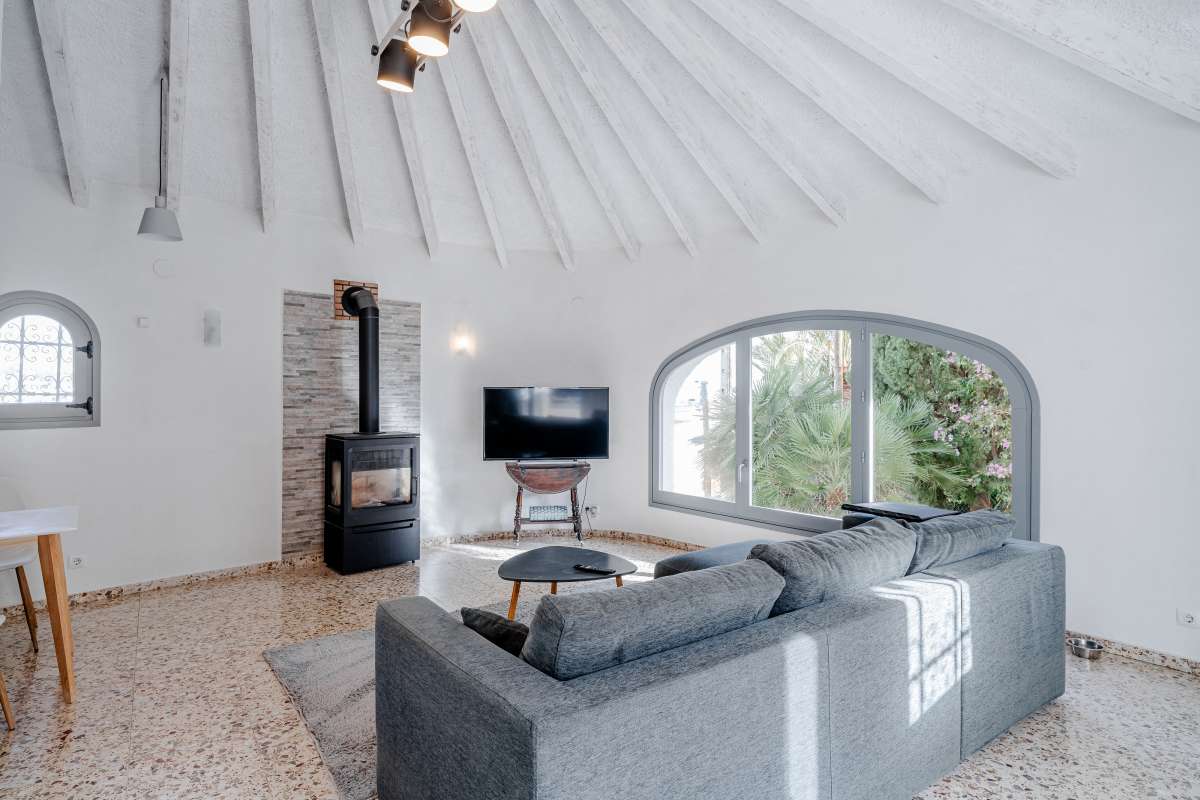 Living room with fireplace, sofa and beamed ceiling inside a Mediterranean villa in Maryvilla, Calpe.