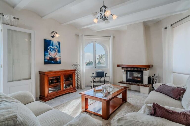 Living room with fireplace, sofa seating and natural light inside a Mediterranean villa with guest accommodation in Calpe.