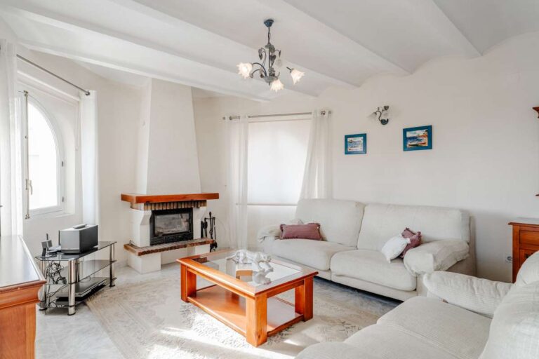 Living room with fireplace, sofa seating and natural light inside a Mediterranean villa with independent guest accommodation in Calpe.