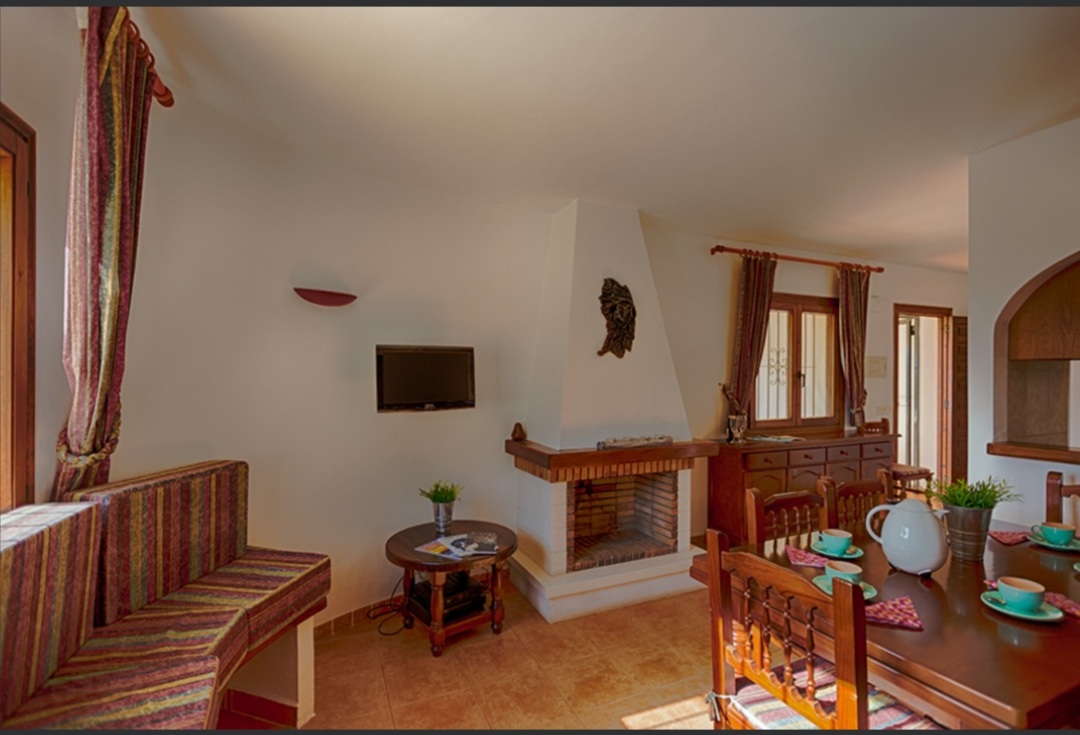 Living room with fireplace, traditional seating and dining area inside a Mediterranean villa in a tranquil residential area of Calpe.