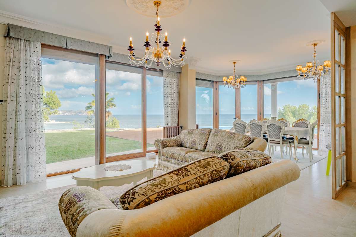 Living room with large windows, natural light and sea views inside a frontline villa in Les Bassetes.