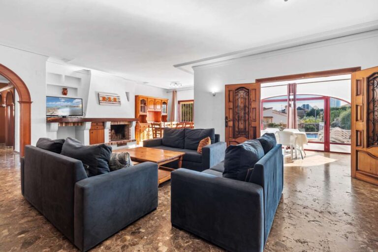 Living room with sofa seating and terrace access inside a spacious villa with guest apartments in Calpe.