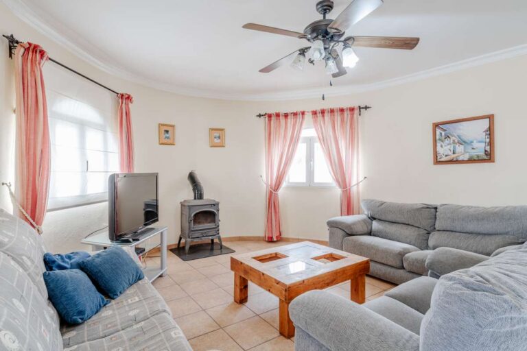 Living room with sofa seating, ceiling fan and natural light inside a Mediterranean villa in Calpe.