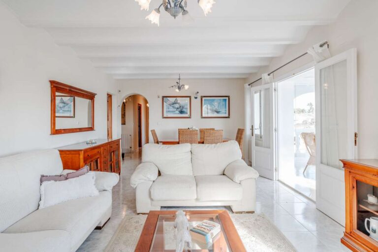 Living room with sofa seating, natural light and terrace access inside a Mediterranean villa with guest accommodation in Calpe.