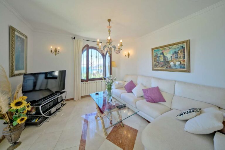 Living room with traditional furniture, arched window and natural light inside a second line Mediterranean villa in Calpe.