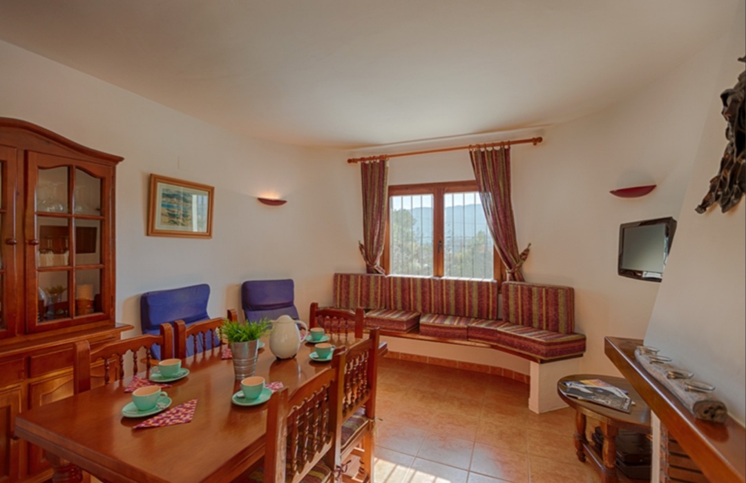 Living room with traditional furniture, natural light and dining area inside a Mediterranean villa with mountain views in Calpe.