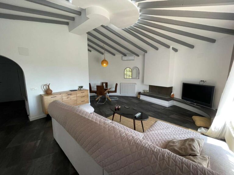 Living room with vaulted ceiling, fireplace and natural light inside a refurbished villa with three independent apartments in Canuta, Calpe.
