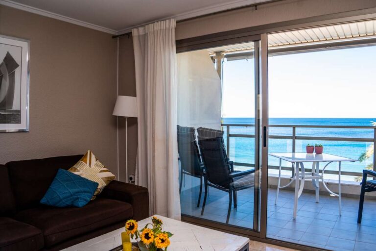 Lounge area inside a beachfront apartment by La Fossa Beach in Calpe with sofa seating, terrace access and Mediterranean Sea views