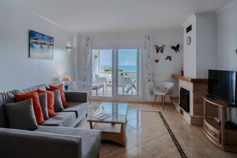 Lounge inside a duplex apartment near Les Platgetes Beach in Moraira with sofa seating, fireplace, terrace access and Mediterranean Sea views