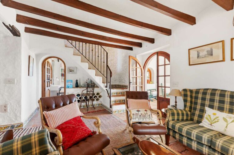 Lounge inside a traditional Spanish finca near Moraira with beamed ceiling, staircase, rustic seating and Mediterranean character