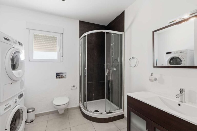 Lower-level bathroom with shower, toilet, and laundry area inside a villa in Calpe