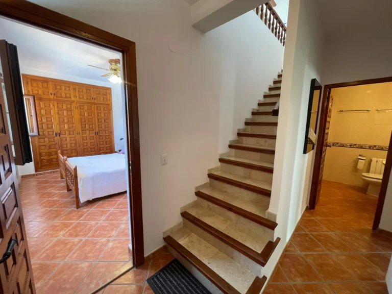 Lower-level hallway with staircase access and bedroom entrance inside a villa in Calpe.