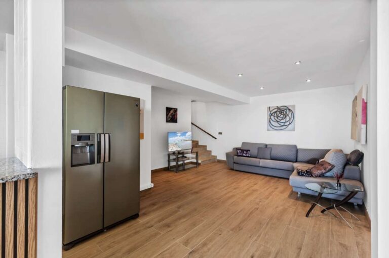 Lower level living area with sofa, open layout and kitchen connection inside a modern spacious villa in Calpe.