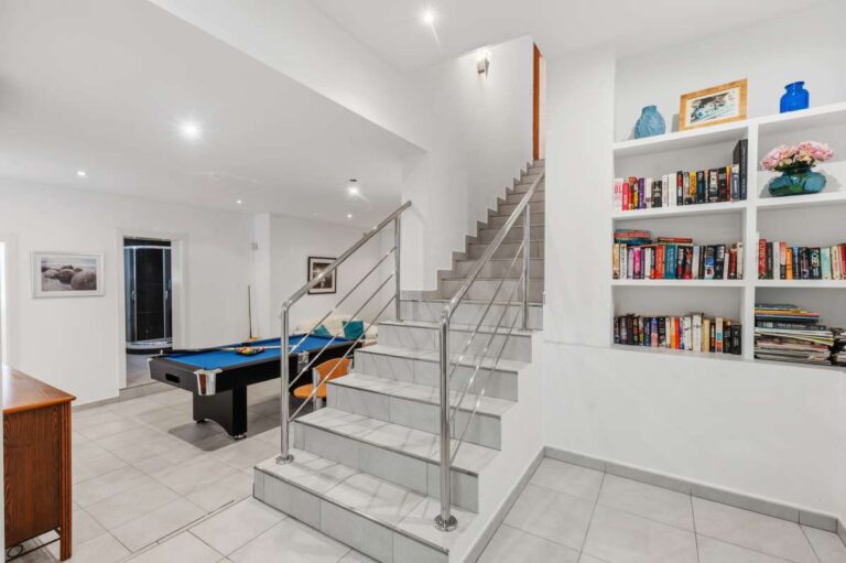 Lower-level living area with staircase, storage, and games space inside a villa in Calpe.