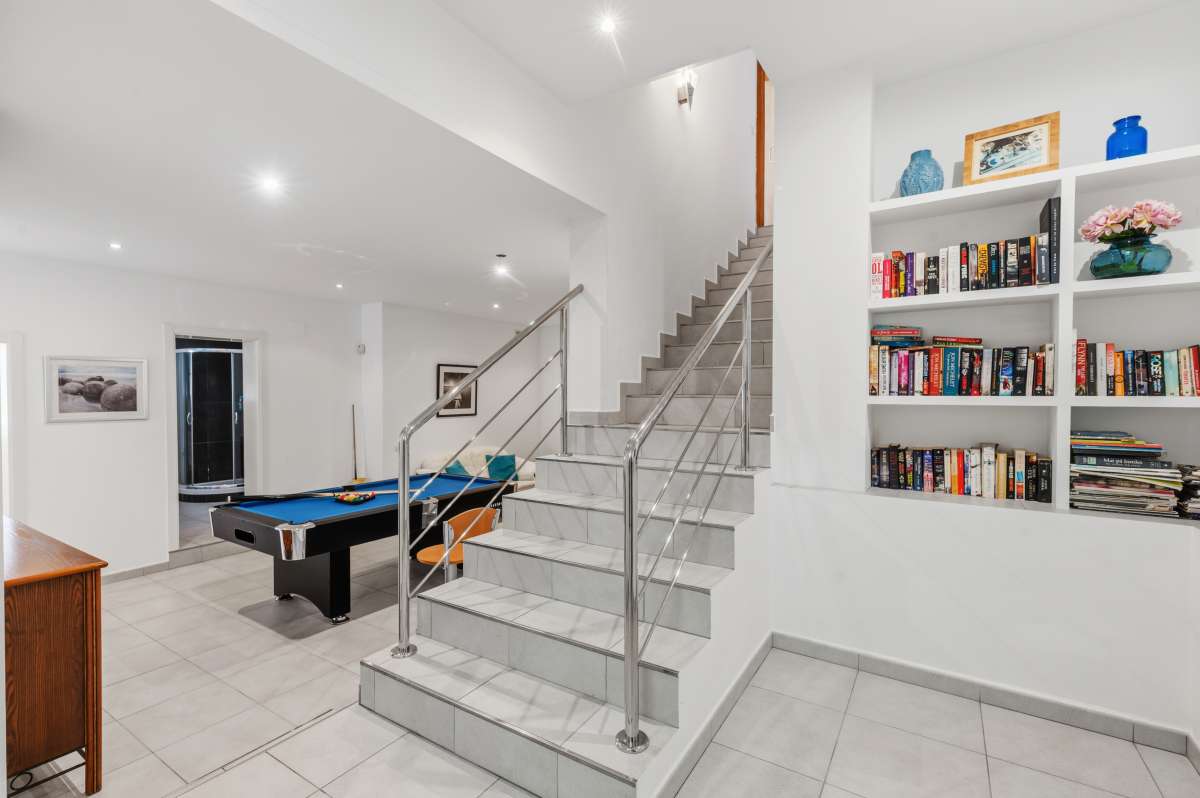 Lower-level living area with staircase, storage, and games space inside a villa in Calpe.