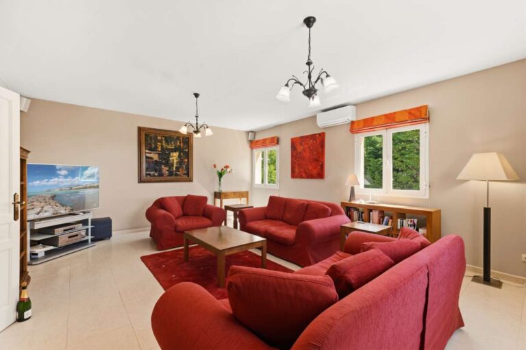 Lower-level living room inside an elegant Mediterranean villa in Altea Hills with red sofas, TV area and bright interior finish