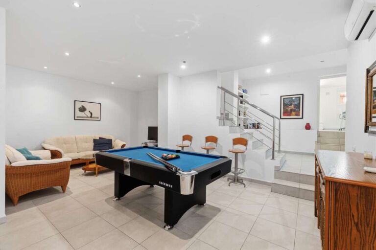Lower-level lounge area with pool table, seating, and interior staircase inside a villa in Calpe.