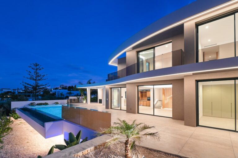 Luxury villa exterior with infinity pool at dusk near La Fustera Beach
