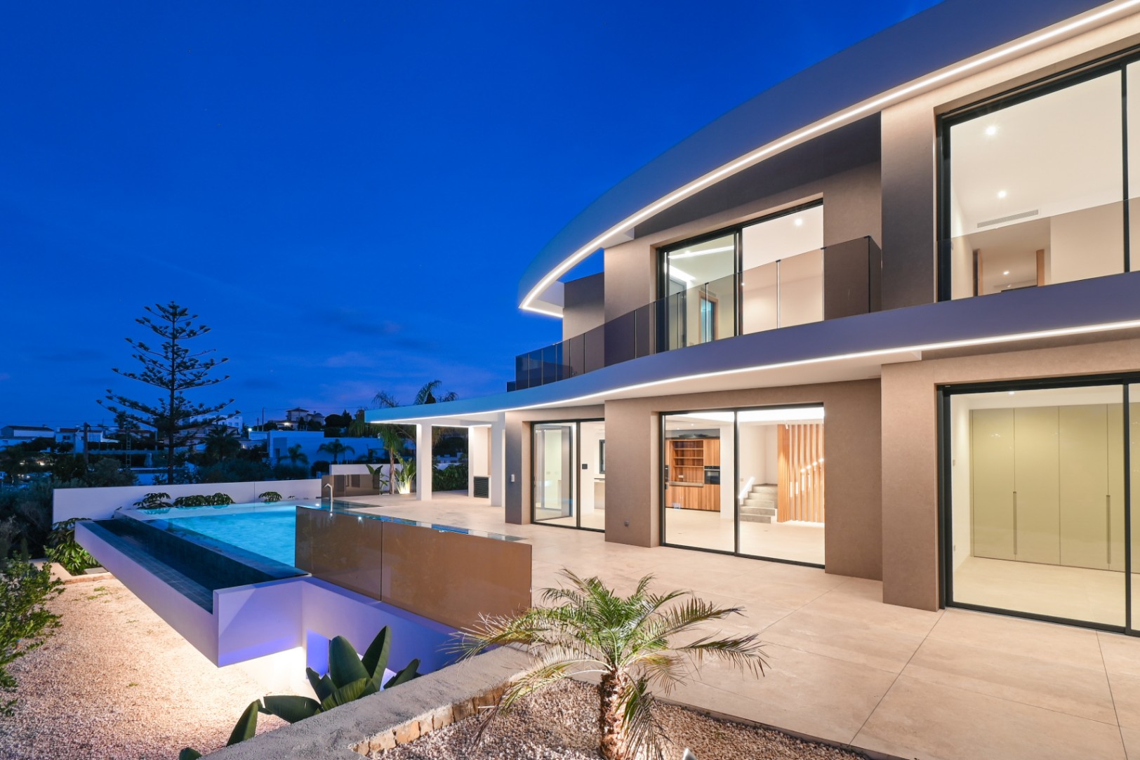 Luxury villa exterior with infinity pool at dusk near La Fustera Beach