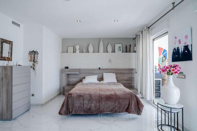 Main bedroom inside a renovated apartment by Arenal-Bol Beach in Calpe with fitted storage, terrace access and modern white interior
