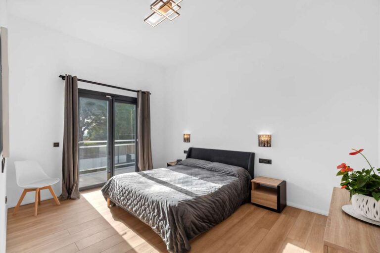 Main bedroom inside a single-level modern villa in Santa Clara, Altea with double bed, wood flooring, terrace access and bright white interior