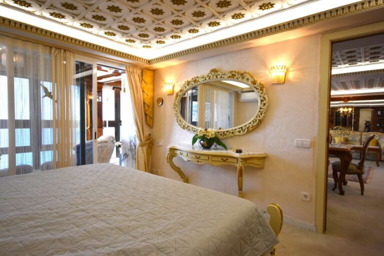 Main bedroom with decorative ceiling, custom-made furniture and access towards the glazed terrace in a frontline Calpe penthouse.