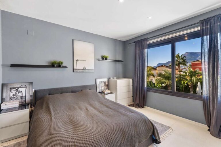Master bedroom with large window, fitted storage and garden views inside a modern oasis villa near Arenal-Bol Beach in Calpe.