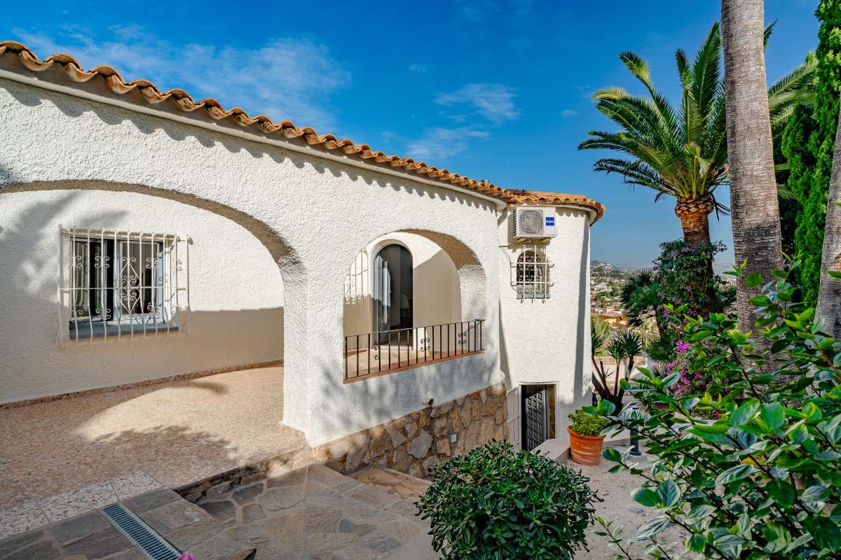 Mediterranean villa exterior with arched balcony, white façade and garden surroundings in Maryvilla, Calpe.