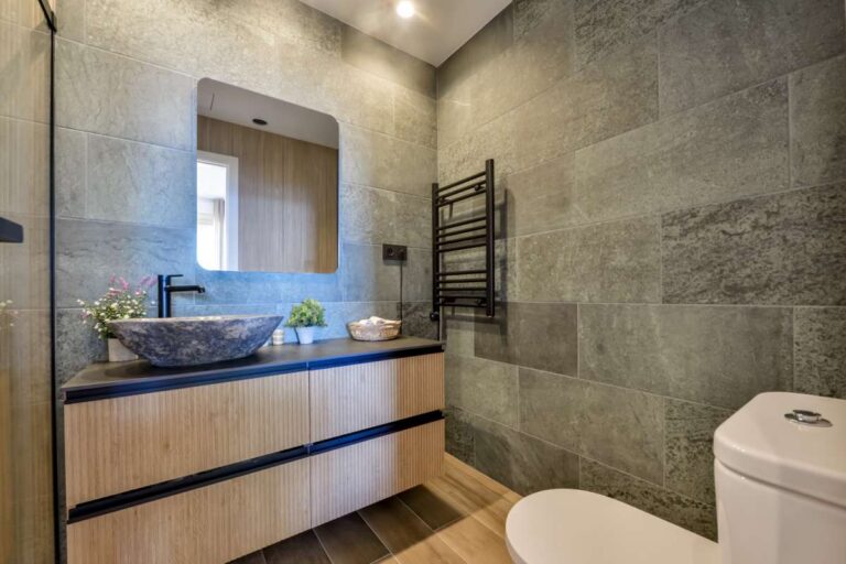 Modern bathroom inside a luxury frontline beach duplex in Mascarat, Altea with vanity unit, mirror, toilet, towel rail and grey tiled finish