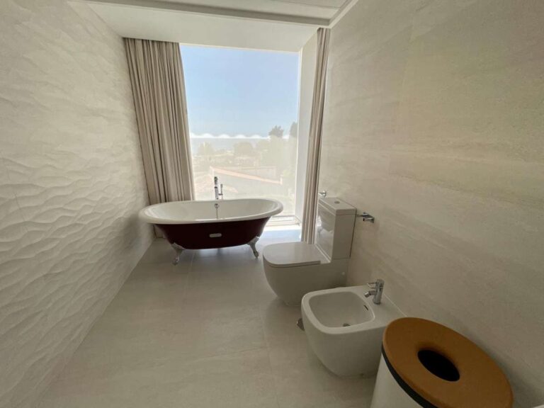 Modern bathroom inside a luxury villa in La Calalga, Calpe with freestanding bath, bidet, large window and contemporary tiled finish