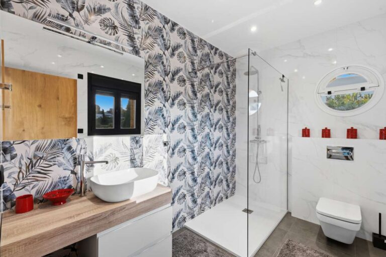 Modern bathroom inside a premium coastal villa on the Benissa Costa with walk-in shower, patterned feature wall, vanity unit and bright tiled finish