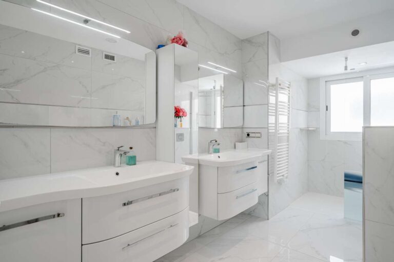 Modern bathroom inside a renovated apartment by Arenal-Bol Beach in Calpe with double vanity, bath and bright white finish