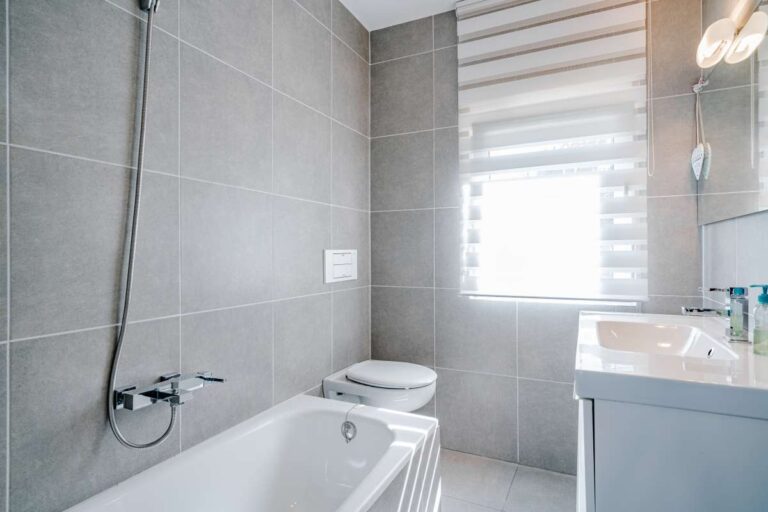 Modern bathroom inside a villa in Calpe with bathtub, shower fitting, vanity unit and window with natural light