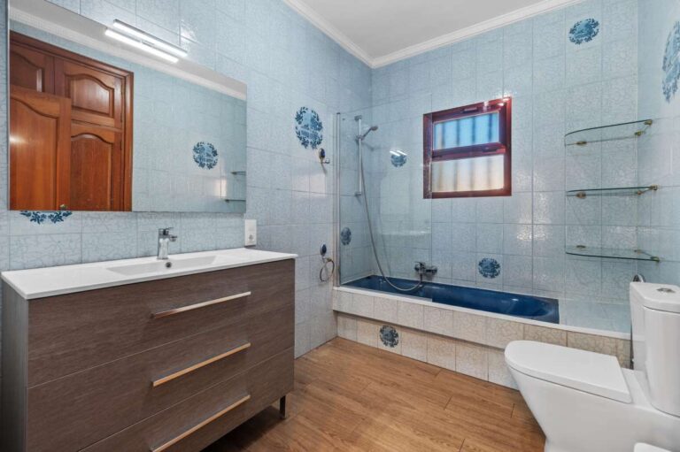 Modern bathroom with bathtub, vanity and natural light inside a spacious villa with guest apartments in Calpe.