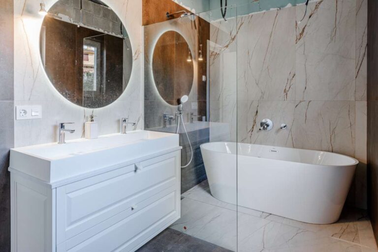 Modern bathroom with freestanding bath, vanity unit and round mirror inside a new build villa in Calpe
