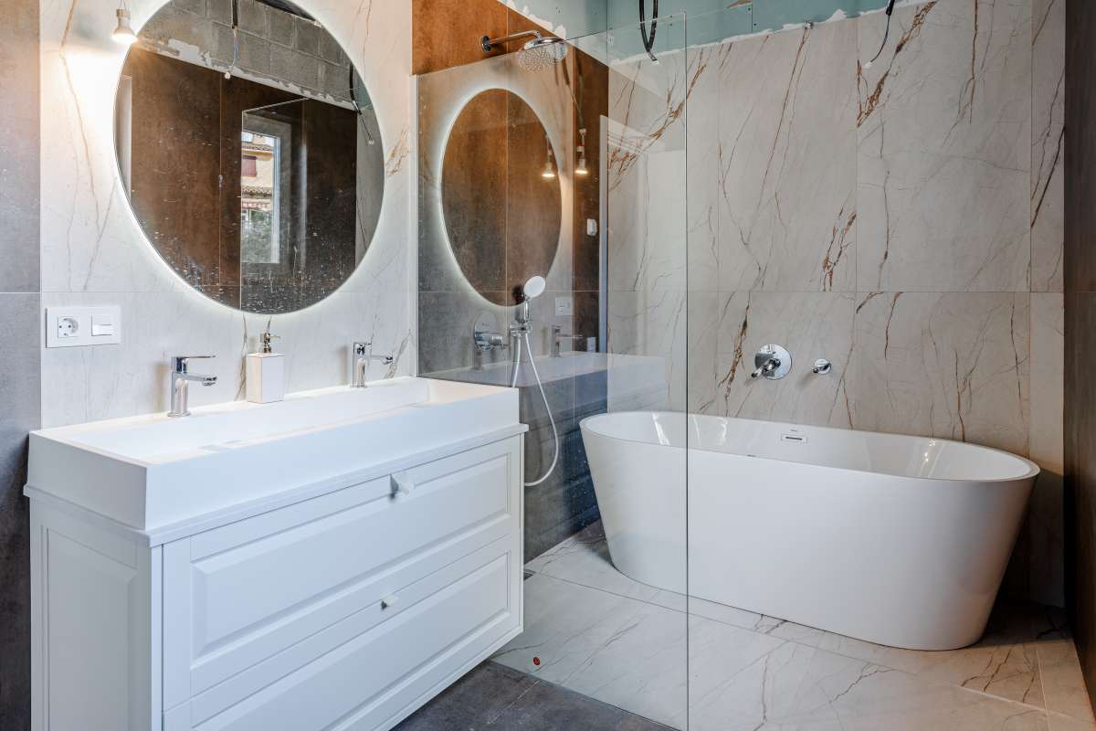 Modern bathroom with freestanding bath, vanity unit and round mirror inside a new build villa in Calpe