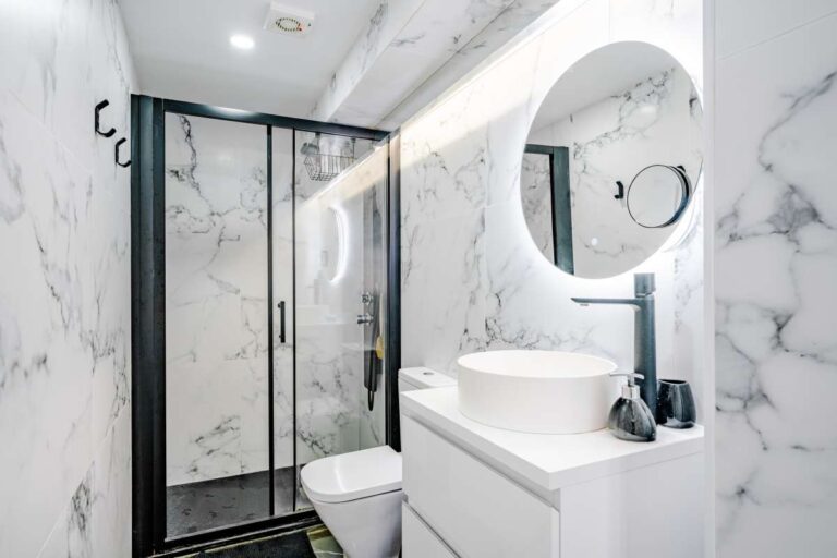 Modern bathroom with walk-in shower, round mirror and marble-effect finish inside a renovated Mediterranean villa in La Cometa, Calpe.
