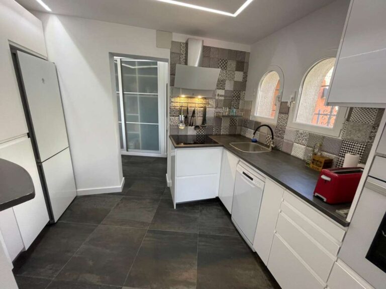 Modern fitted kitchen with white cabinets and natural light inside a refurbished villa in Canuta, Calpe.