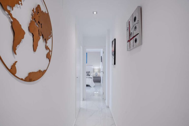 Modern hallway inside a renovated Arenal-Bol apartment in Calpe with white interior, wall decor and bedroom access